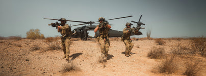 Three soldiers advance with rifles across a desert, black helicopter behind them, ready for tactical execution.