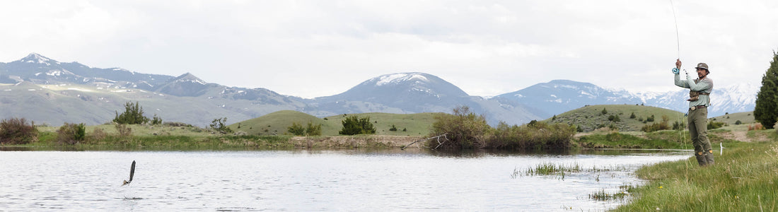 Eduardo Garcia fly fishing on the banks of a mountain river with snow-capped peaks in the background